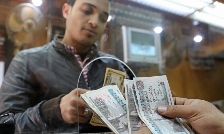 a customer exchanges u.s. dollars to egyptian pounds in a foreign exchange office in central cairo